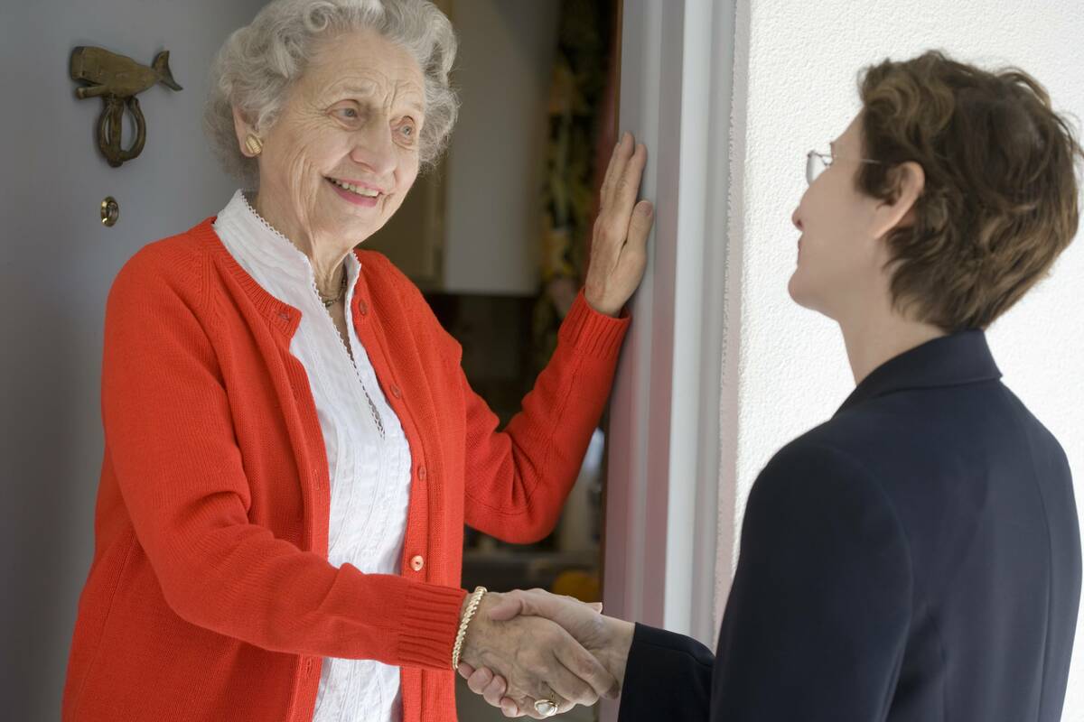 senior woamn shaking hands with salesperson at door