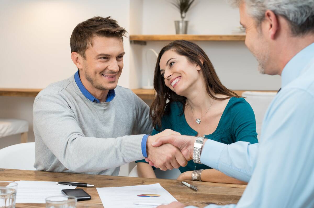Happy young couple shaking hands for a financial agreement